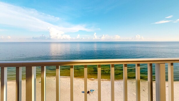 A beach view from a balcony with a railing, clear sky, and calm sea. - Inviting Gulf-front condo In Perdido Key with waterfront pool/hot tub and oceanfront balcony (Perdido Key)