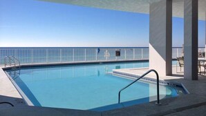 A pool with a clear view of the ocean, surrounded by a white railing and a shaded area with chairs. - Inviting Gulf-front condo In Perdido Key with waterfront pool/hot tub and oceanfront balcony (Perdido Key)