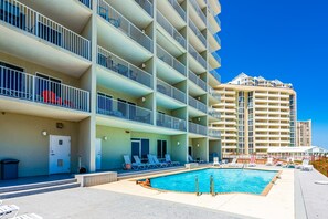 A hotel with a swimming pool, multiple balconies, and a view of other buildings. - Oceanfront Condo with Shared Pool, Ocean View, WiFi, Central AC, and Private W/D (Perdido Key)