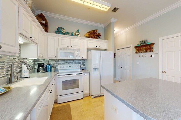 A kitchen with white cabinets, a microwave, stove, refrigerator, and a coffee maker. - Dream escape with beach access, pool, bikes screened patio (Santa Rosa Beach)