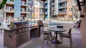 Een dakterras met een zwembad, een barbecue en comfortabele lounge fauteuils.