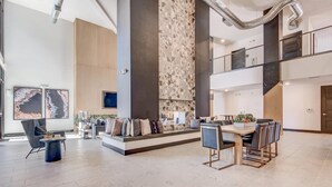 Een ruim, modern interieur met een centraal zithoek, hoge plafonds en zichtbare leidingwerk.