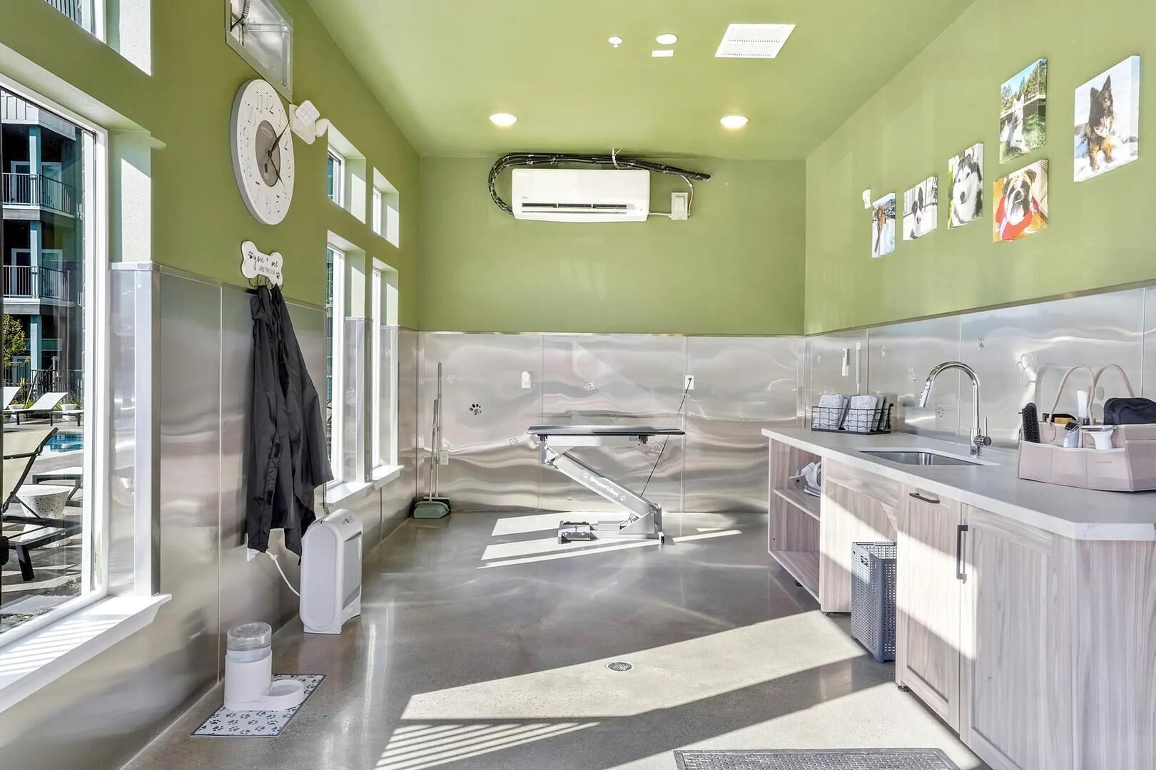 A modern bathroom with a large bathtub, a sink with a mirror, and a window with a view of a pool.