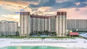 Ein Hochhaus-Hotel mit Blick auf den Strand, das einen großen Pool und mehrere Balkone bietet.
