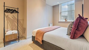 A bedroom with a bed, a window with blinds, a towel rack, and a bedside table. - The Chic Escape in Leeds (Leeds)