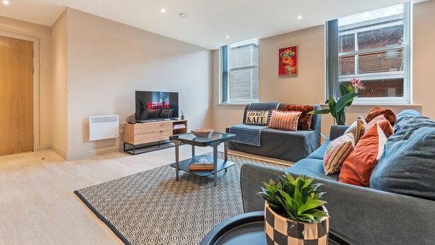 A modern living room with a sofa, a coffee table, a TV, and a window with blinds. - The Chic Escape in Leeds (Leeds)