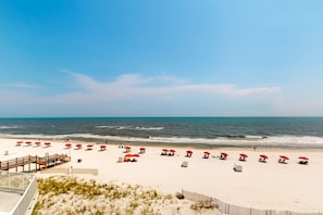 A beach with red umbrellas and a wooden walkway leading to the water. - Inviting Gulf-front condo In Perdido Key with waterfront pool/hot tub and oceanfront balcony (Perdido Key)