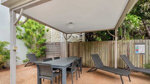 Een terras buiten met een tafel en stoelen, een houten hek en een bord over reanimatie en EHBO.