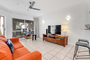Ein modernes Wohnzimmer mit einer Couch, einem Fernseher und einem Deckenventilator.