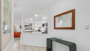 Een moderne keuken met witte kastjes, een zwart aanrecht en een spiegel aan de muur.