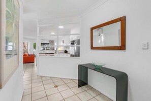 A modern kitchen with white cabinets, a black countertop, and a mirror on the wall. - Yasmin at Coral Horizons: Retro Vibes on the Beach (Palm Cove)