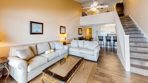 Ein geräumiges Wohnzimmer mit einer Couch, einem Couchtisch und einer Treppe, die in eine obere Etage führt.