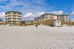 A beachfront hotel with multiple balconies, a lifeguard tower, and a sandy beach. - Dog-friendly 4th-floor 3-bedroom condo with stunning Gulf views & pickleball (Santa Rosa Beach)
