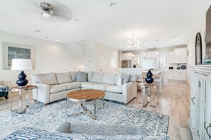 A modern living room with a sectional sofa, a coffee table, and a patterned rug. - Dog-friendly townhouse with two pools, hot tub, easy beach access, bikes, & deck (Perdido Key)
