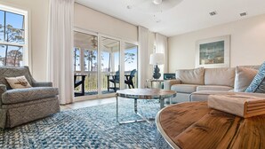 Ein geräumiges Wohnzimmer mit großem Fenster, einer Couch, einem Couchtisch und einem Balkon mit Gartenmöbeln.