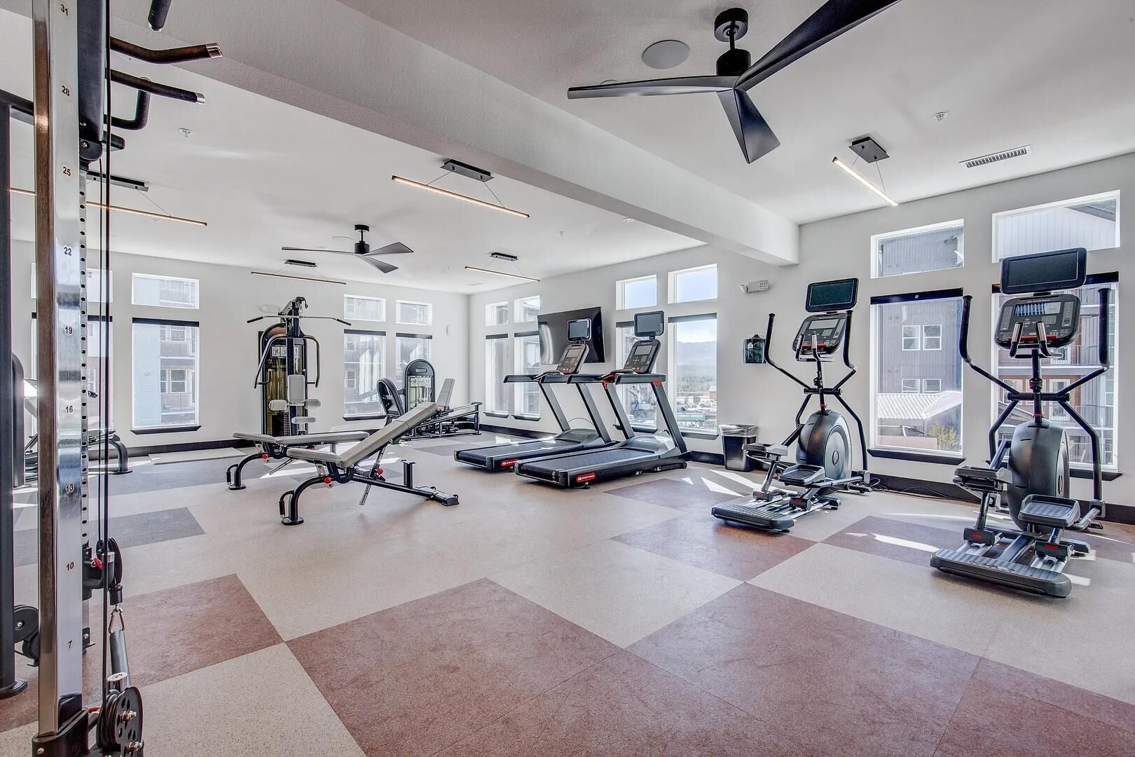 A modern gym with treadmills, elliptical machines, and weightlifting equipment.