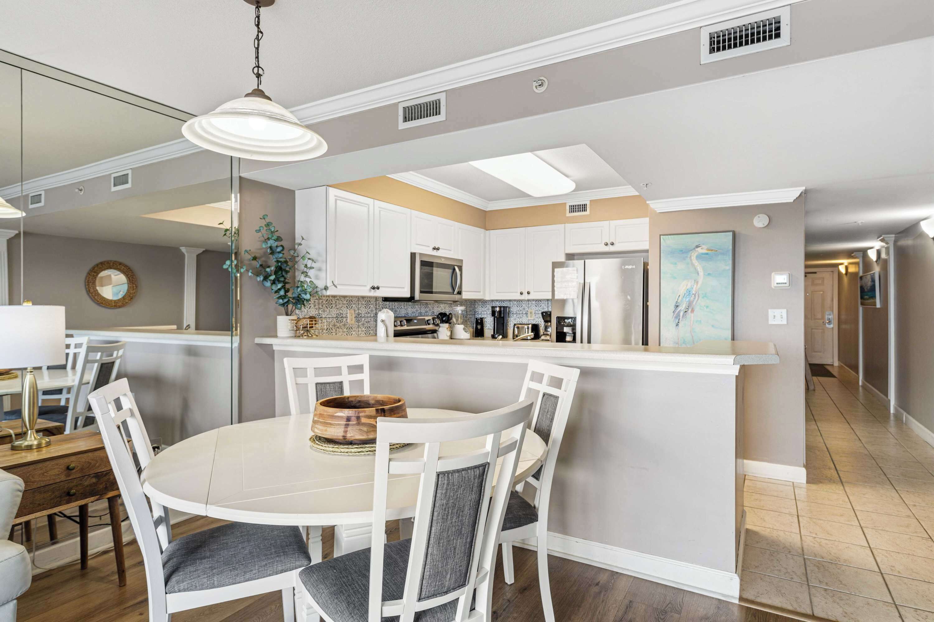 Een moderne keuken met witte kasten, een centraal eiland en een eethoek met witte stoelen.