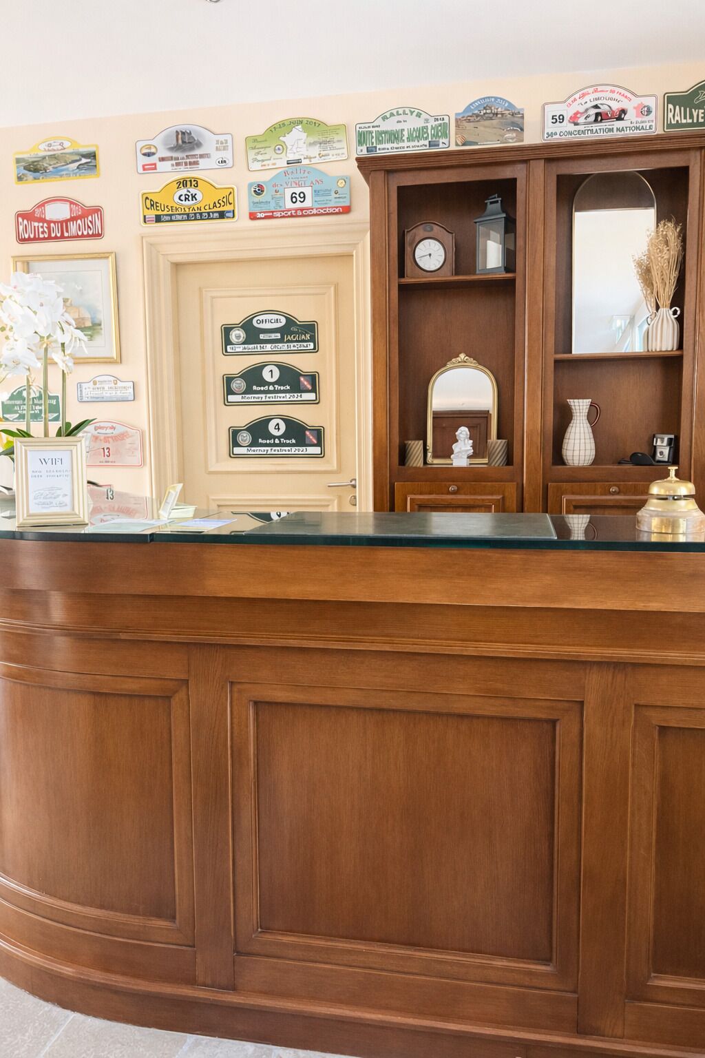 Un comptoir d’accueil avec un revêtement en bois, une horloge et divers panneaux encadrés accrochés au mur.