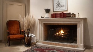 Una habitación con chimenea, una silla, una alfombra y un cuadro en la pared.