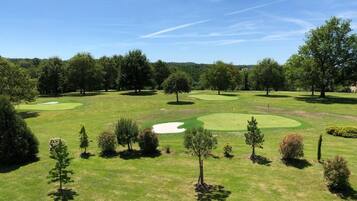 Un campo de golf con varios greens, búnkeres de arena y árboles.