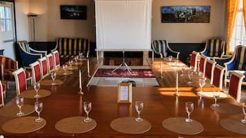 A conference room with a long table, red upholstered chairs, and a white projection screen.