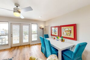 A dining area with a white table, blue chairs, and two framed pictures on the wall. - Cozy, top-floor beachfront condo with pool, pool spa, & beach access (Perdido Key)