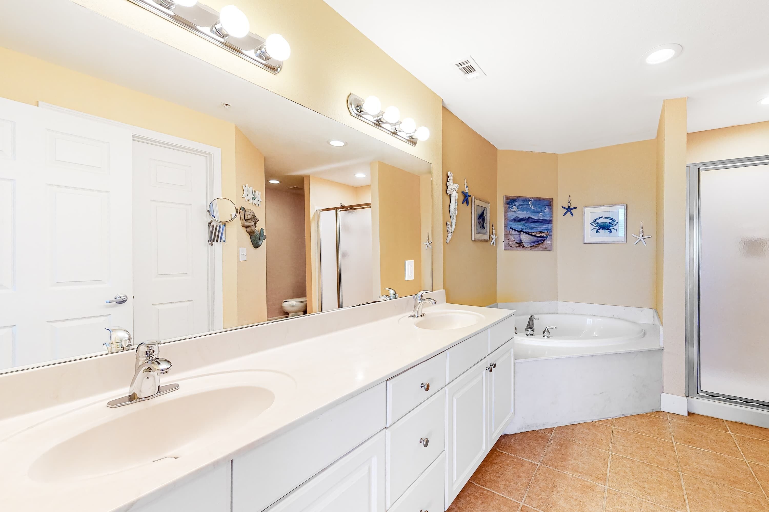 A bathroom with a large mirror, two sinks, a bathtub, and a shower.