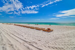 A beach with wooden lounge chairs arranged in rows. - 8th-Floor studio in beachfront resort with outdoor pool, game room, gym, patio (Panama City Beach)