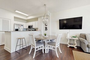A modern kitchen with white cabinets, a central island, and a chandelier. - Oceanfront condo with pool, hot tub, splash pad & gym - great location (Panama City Beach)