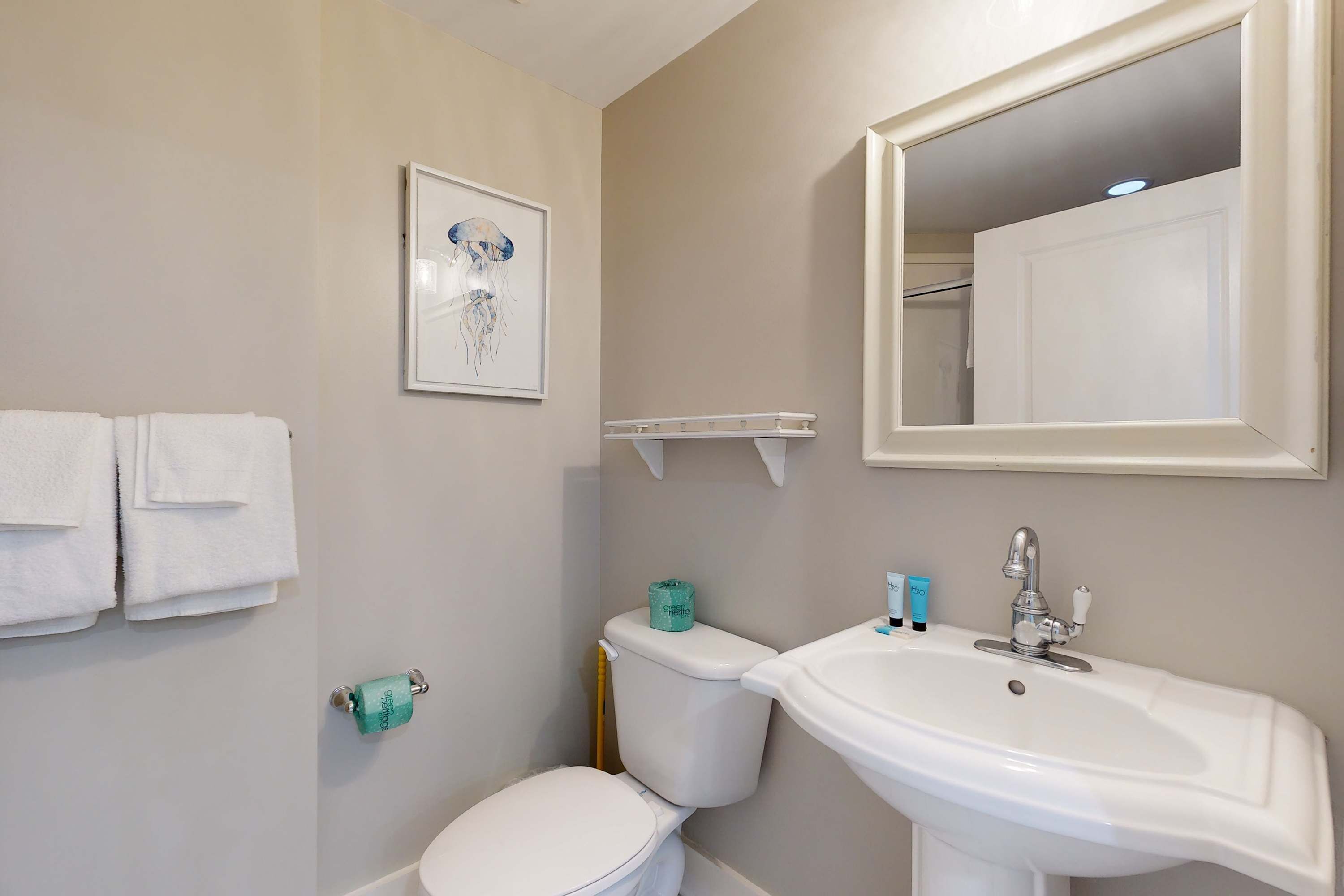 Een badkamer met toilet, wastafel en een foto in een lijst aan de muur.