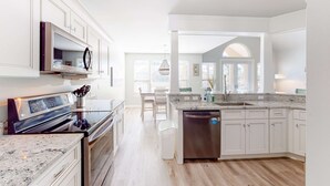 Una cocina moderna con armarios blancos, horno integrado y lavavajillas de acero inoxidable.