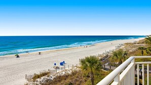A beach with a clear view of the ocean, a sandy beach, and a few people walking.