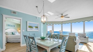 A dining area with a glass table, chairs, and a view of the ocean.