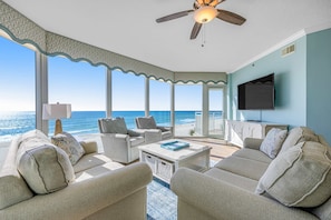 A spacious living room with a view of the ocean, a ceiling fan, and a flat-screen TV. - Picture-Perfect Beach-Front Condo At Waterscape 490 Feet Of Private Beach (Fort Walton Beach)