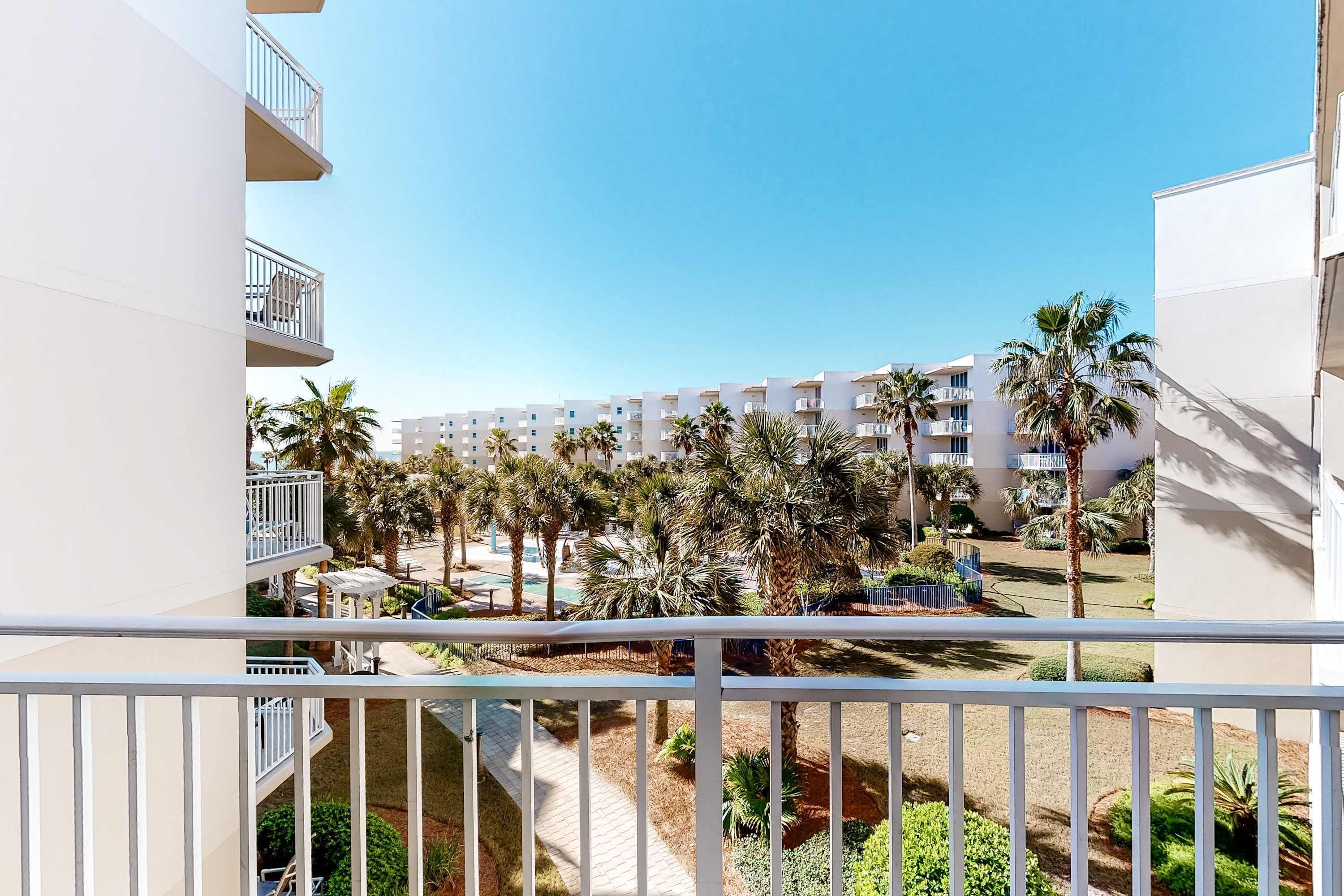 Un balcone con vista su un cortile con palme e un edificio sullo sfondo.