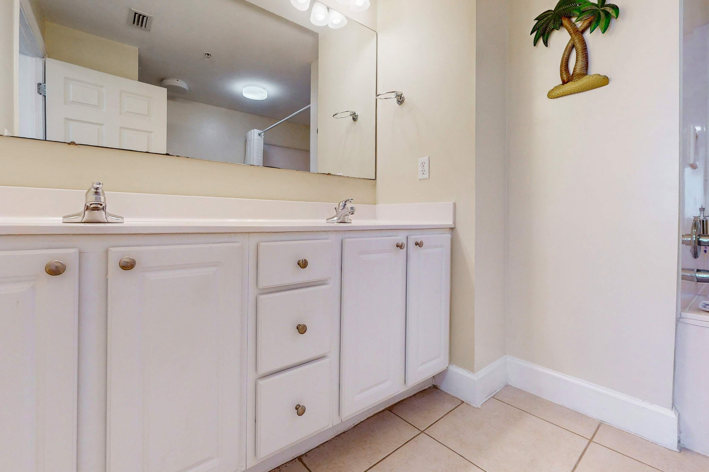 A bathroom with a white vanity, a large mirror, and a wall-mounted toilet.