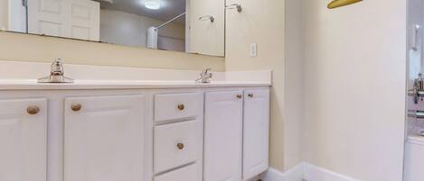 A bathroom with a white vanity, a large mirror, and a wall-mounted toilet.