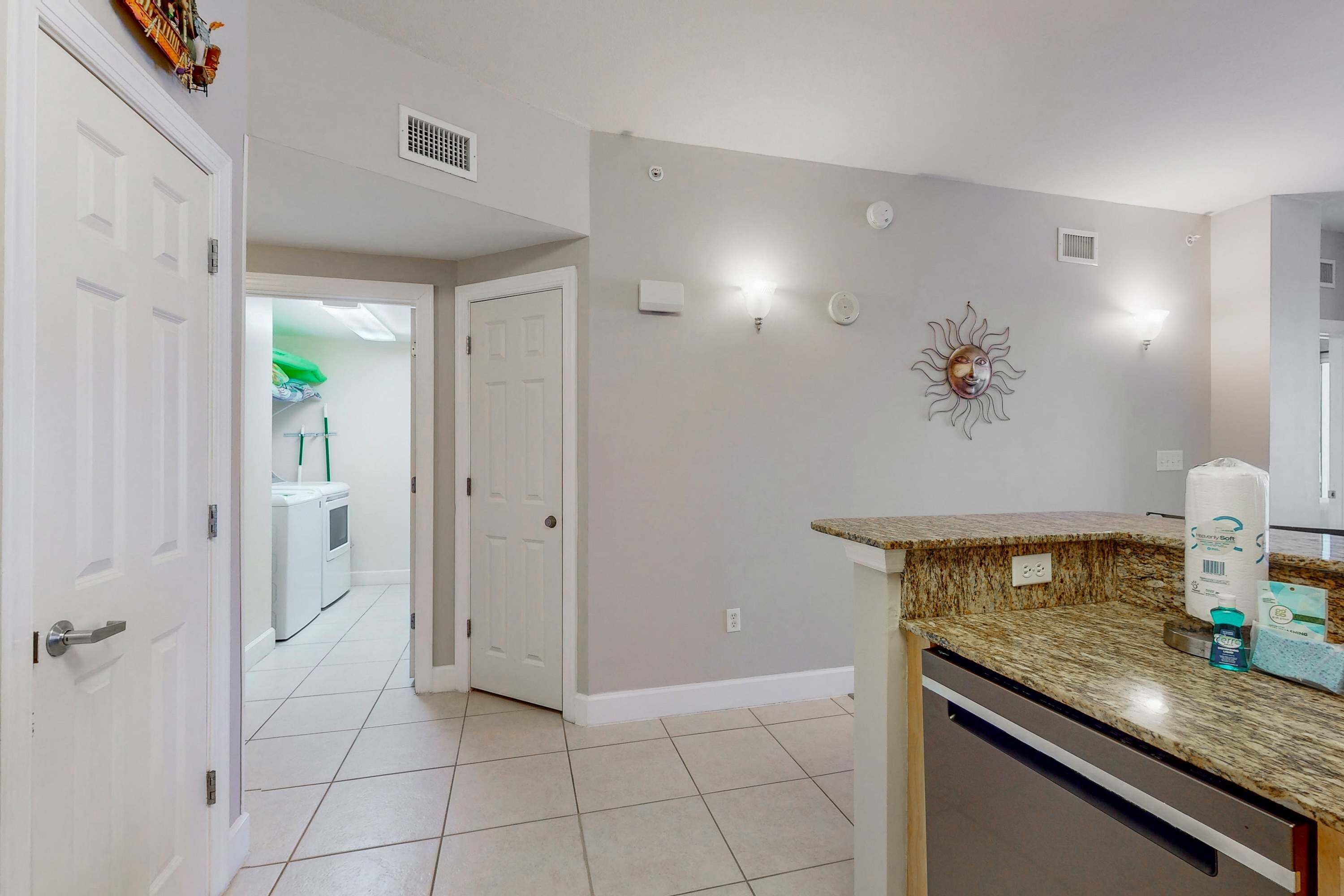 A clean, modern kitchen with a granite countertop, white cabinets, and a built-in dishwasher.