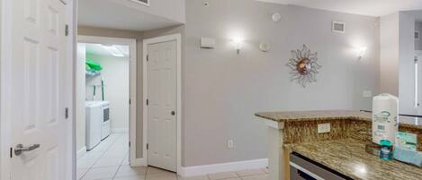 A clean, modern kitchen with a granite countertop, white cabinets, and a built-in dishwasher.