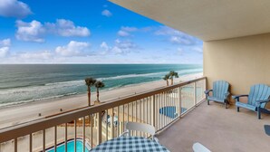 Un balcon équipé d’une table de billard, de deux fauteuils Adirondack et offrant une vue sur la plage et l’océan.