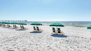 A beach with rows of green umbrellas and lounge chairs. - Sunny Waterscape ground-floor condo with pools, hot tubs, & stunning Gulf views (Fort Walton Beach)