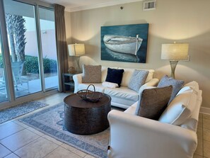 A modern living room with a white sofa, a coffee table, and a painting of a boat. - Sunny Waterscape ground-floor condo with pools, hot tubs, & stunning Gulf views (Fort Walton Beach)