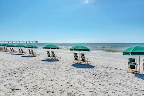 A beach with rows of green umbrellas and lounge chairs. - Fifth Floor Condo with Gulf Views, Shared Pool and Hot Tub, and High-Speed WiFi (Fort Walton Beach)