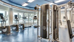 Uma academia moderna com diversos equipamentos de exercício, amplas janelas e um interior limpo e bem iluminado.