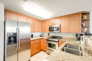 A kitchen with wooden cabinets, stainless steel appliances, granite countertops, and a built-in sink. - 5th Floor Beautifully Decorated Condo At Waterscape Waterfall, Lazy River (Fort Walton Beach)