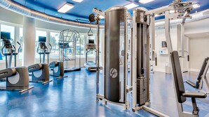 Una palestra con diverse macchine per esercizi, un ampio specchio e una finestra che lascia entrare luce naturale.