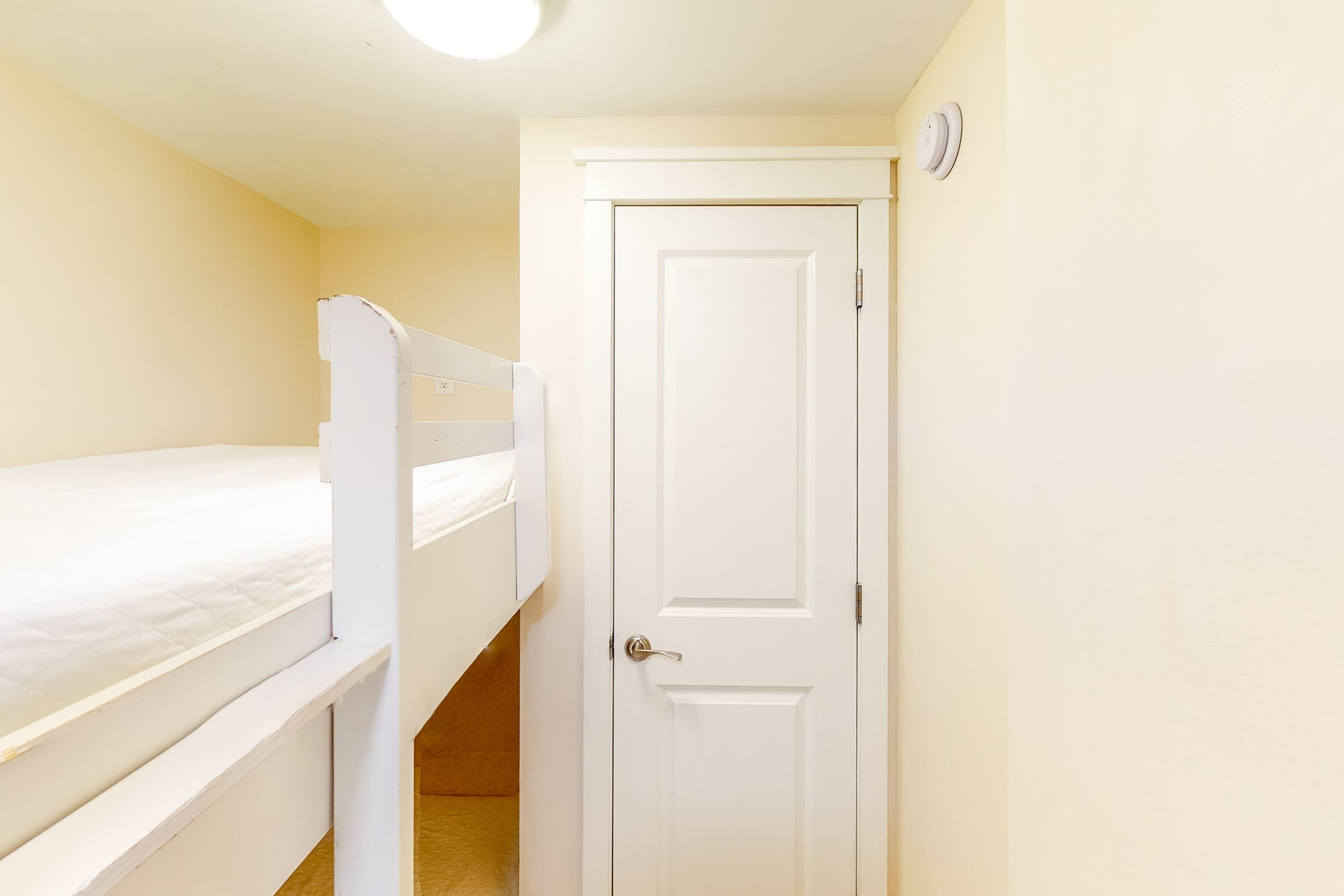 A small room with a bunk bed and a door.