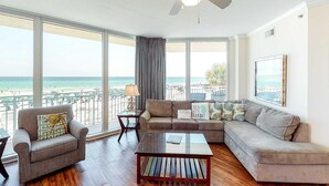 Ein großzügiger Wohnraum mit großem Fenster mit Blick auf den Strand, einem Deckenventilator und einer modernen Sofagarnitur.