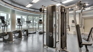 Ett gym med olika typer av träningsutrustning, inklusive löpband, en styrketräningsmaskin och en stång för chins.