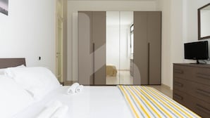 A hotel room with a bed, a wardrobe, a television, and a bathroom visible through a door.